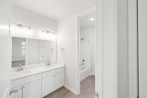 Bathroom with washtub / shower combination, vanity, and tile patterned flooring