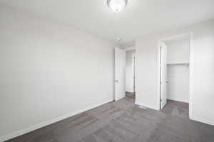 Unfurnished bedroom with a walk in closet, carpet floors, and a closet