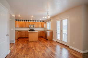 Kitchen featuring sink, a center island, hanging light fixtures, appliances with stainless steel finishes, and hardwood / wood-style flooring