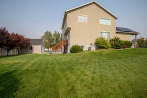 Rear view of house featuring a yard, solar panels, and central air condition unit