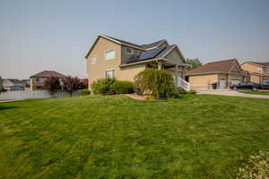 View of front of home with a front lawn and solar panels