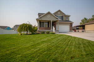 View of front facade featuring a garage and a lawn