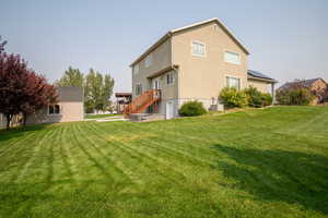 Back of house with central AC and a lawn