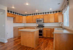 Kitchen featuring stainless steel appliances, dark hardwood / wood-style flooring, a center island, and sink