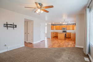 Kitchen featuring light brown cabinetry, sink, a center island, light carpet, and appliances with stainless steel finishes