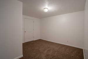 Carpeted empty room featuring a textured ceiling