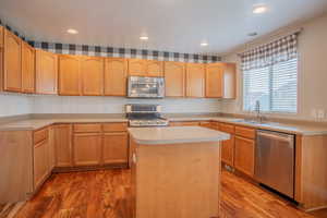 Kitchen featuring sink, hardwood / wood-style floors, stainless steel appliances, and a center island