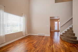 Unfurnished living room with a towering ceiling and wood-type flooring