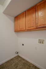 Laundry room with cabinets, hookup for an electric dryer, dark tile patterned floors, and washer hookup