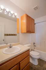 Full bathroom with vanity, tile patterned floors, shower / washtub combination, and toilet