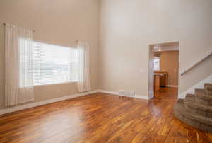 Empty room featuring a towering ceiling and wood-type flooring