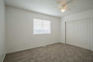 Unfurnished bedroom featuring ceiling fan, a closet, and carpet