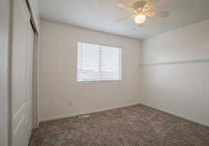 Unfurnished bedroom with a closet, ceiling fan, and carpet flooring