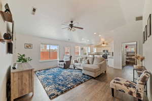 Living room with vaulted ceiling, ceiling fan, and hardwood / wood-style floors