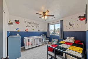 Carpeted bedroom with a textured ceiling and ceiling fan