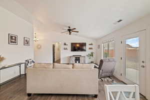 Living room with vaulted ceiling, ceiling fan, and dark hardwood / wood-style flooring