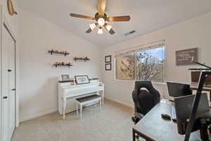 Office area featuring ceiling fan, lofted ceiling, and light carpet