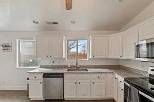 Kitchen featuring white cabinetry, appliances with stainless steel finishes, sink, and light stone counters