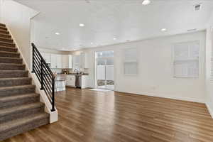 Unfurnished living room featuring sink, light hardwood / wood-style flooring, and a textured ceiling