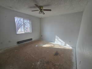 Unfurnished room featuring ceiling fan, a textured ceiling, and a baseboard heating unit