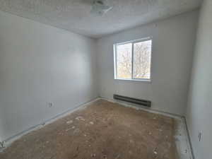 Unfurnished room with baseboard heating and a textured ceiling