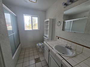 Full bathroom featuring tile patterned flooring, bath / shower combo with glass door, vanity, a textured ceiling, and toilet