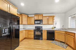 Kitchen featuring sink, light wood-type flooring, and black appliances