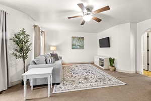 Carpeted living room featuring ceiling fan