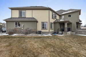 Back of house with central AC unit and lawn