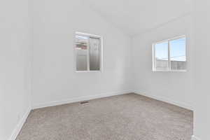 Carpeted spare room with vaulted ceiling