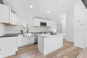 Kitchen featuring stainless steel appliances, a center island, sink, and white cabinets