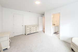 Bedroom with ensuite bathroom, sink, and light carpet