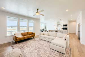 Living room featuring sink, a water view, a textured ceiling, and light wood-type flooring