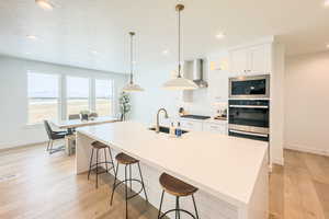 Kitchen with black gas cooktop, built in microwave, an island with sink, sink, and white cabinets