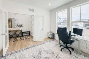 Office space with french doors and light hardwood / wood-style flooring