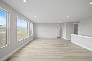 Unfurnished living room with a mountain view and light hardwood / wood-style floors