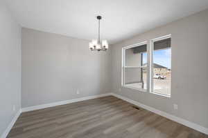 Unfurnished room with an inviting chandelier and hardwood / wood-style floors