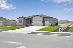 Single story home with an attached garage, a mountain view, and driveway