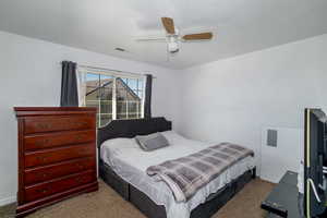 Bedroom featuring light carpet, a textured ceiling, and ceiling fan