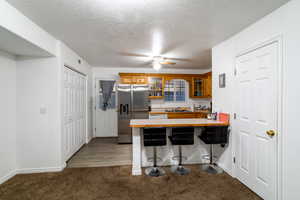 Kitchen featuring sink, a kitchen breakfast bar, dark colored carpet, stainless steel fridge with ice dispenser, and kitchen peninsula