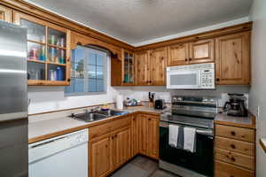 Kitchen with stainless steel appliances, wood-type flooring, sink, and a textured ceiling