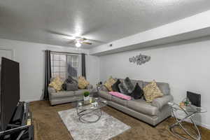 Carpeted living room featuring a textured ceiling and ceiling fan