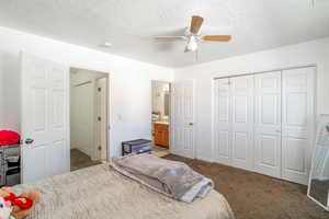 Bedroom with ceiling fan, carpet, a textured ceiling, and a closet