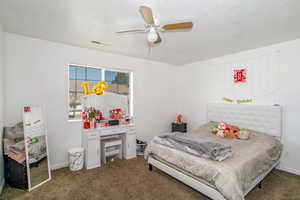 Bedroom with ceiling fan, carpet, and a textured ceiling