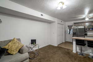 Interior space with dark carpet, stainless steel fridge, and a textured ceiling