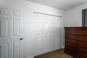 Bedroom with a closet and dark colored carpet