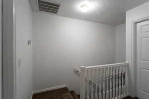 Stairway with carpet flooring and a textured ceiling