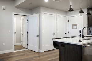 Kitchen with wood-type flooring, decorative light fixtures, dishwasher, and sink