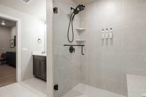 Bathroom featuring tile patterned flooring, vanity, and walk in shower