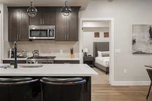 Kitchen featuring a kitchen bar, sink, hanging light fixtures, light hardwood / wood-style flooring, and backsplash